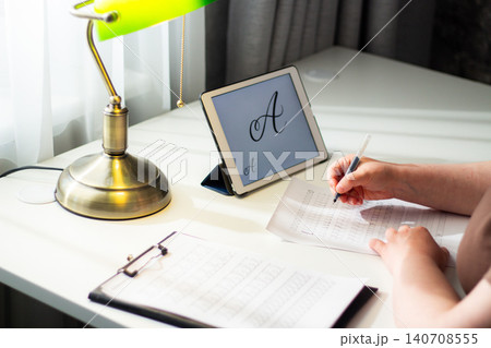 Person seated at desk deeply focused on writing in notebook. Physical engagement of motor skills Handwriting as brain training. Prevention of age related cognitive decline. Senior or adult practicing Person seated at desk deeply focused on writing in notebook. Physical engagement of motor skills Handwriting as brain training. Prevention of age related cognitive decline. Senior or adult practicing 140708555