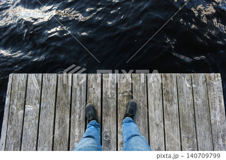 A person wearing jeans and black sneakers, top view 140709799