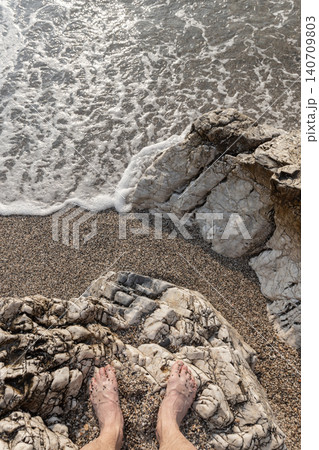 Bare feet rest on white-veined rocks and pebbles Bare feet rest on white-veined rocks and pebbles 140709803