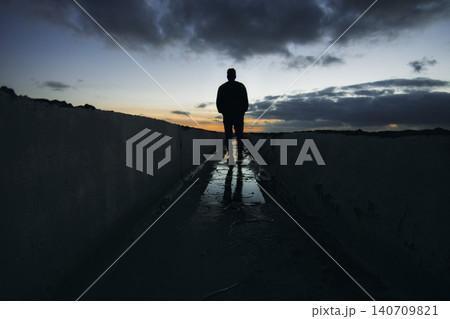 Solitary man walking at sunset with dramatic sky Solitary man walking at sunset with dramatic sky 140709821