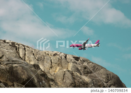 Wizz air airplane flying over rocky cliff under clear sky Wizz air airplane flying over rocky cliff under clear sky 140709834
