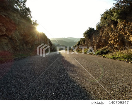 Asphalt road winding through mountains at sunset Asphalt road winding through mountains at sunset 140709847