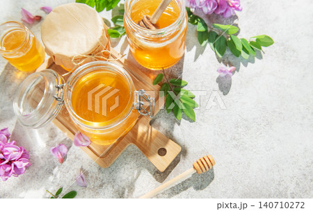 Golden acacia honey in jars with dipper, flowers Golden acacia honey in jars with dipper, flowers 140710272