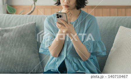 スマートフォンを使いながら考える女性 スマートフォンを使いながら考える女性 140710467