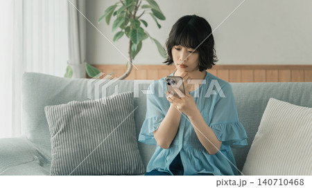 スマートフォンを使いながら考える女性 スマートフォンを使いながら考える女性 140710468