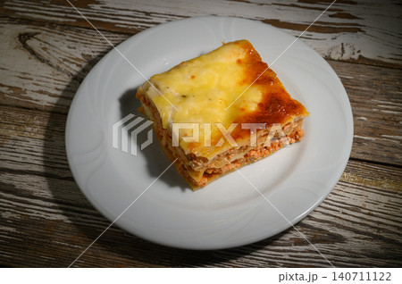 Deliciously baked layers of meat and cheese create a perfect comfort food experience at a cozy dinner setting Deliciously baked layers of meat and cheese create a perfect comfort food experience at a cozy dinner setting 140711122