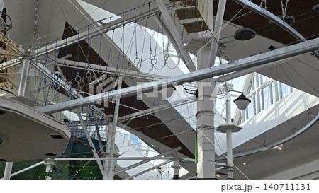 An empty indoor rope course for diverse users of all ages and genders with metal beams and safety gear. An empty indoor rope course for diverse users of all ages and genders with metal beams and safety gear. 140711131