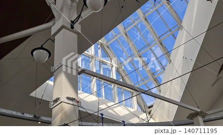 Modern architectural interior with white columns and large glass skylight under clear blue sky. Modern architectural interior with white columns and large glass skylight under clear blue sky. 140711195