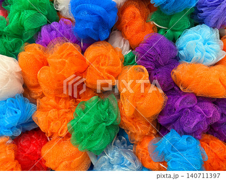 Colorful assortment of multicolored mesh bath sponge poufs piled together in a market Colorful assortment of multicolored mesh bath sponge poufs piled together in a market 140711397