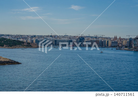 Panoramic Sliema Malta coastal skyline across blue Marsamxett Harbour with sailing boats yachts and modern waterfront buildings 140711561