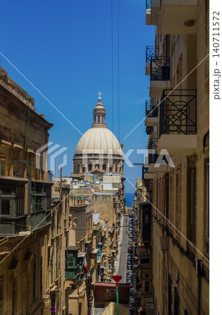 Dome of Carmelite Church Basilica framed by narrow Valletta street Malta with traditional buildings balconies and sea view 140711572