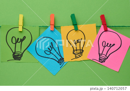 Multicolored stickers with pictures of light bulbs are fastened with blue paper clips Multicolored stickers with pictures of light bulbs are fastened with blue paper clips 140712057