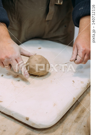 Clay shaping. Pottery workshop. Unrecognizable woman artisan creative hand cutting raw with thread using in ceramic artistic workplace. 140712116