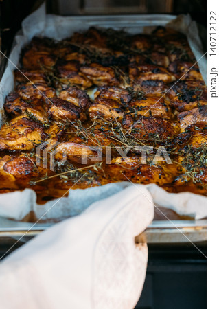 Meal cooking. Roasting meat. Chef hand in oven mitten holding baking tray with well done prepared pork dish garnished with aroma herbs. Meal cooking. Roasting meat. Chef hand in oven mitten holding baking tray with well done prepared pork dish garnished with aroma herbs. 140712122