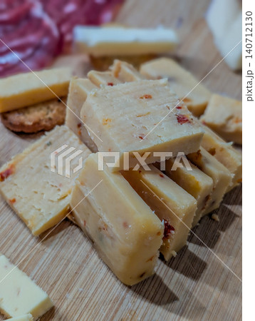 Sliced Semi Hard Cheese on Wooden Cutting Board Close Up Sliced Semi Hard Cheese on Wooden Cutting Board Close Up 140712130