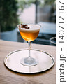 Served drink. Bright beverage. Orange cocktail with frothy white top in stemmed glass. Refreshing mix with aroma flavor on outdoor bar table. 140712167