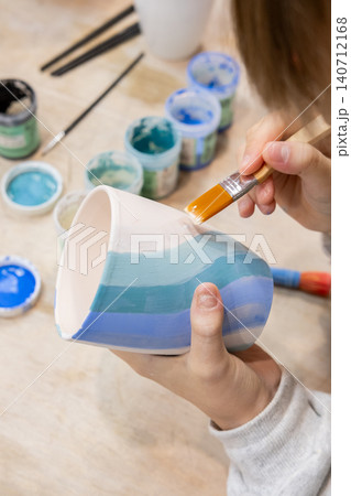 Ceramic art. Pottery class. Unrecognizable talented child hand painting on cup using brush developing creative skill in artisan workshop. Ceramic art. Pottery class. Unrecognizable talented child hand painting on cup using brush developing creative skill in artisan workshop. 140712168