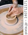 Ceramic craft. Sculpting clay. Unrecognizable professional woman hands modeling pot for artisan art using wheel in pottery workshop. 140712171