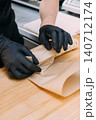 Wrapping fast food. Preparing shawarma. Gloved chef hand packing meal in culinary paper on wooden table. Professional kitchen service. 140712174