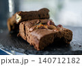 Nut brownie. Chocolate dessert. Sweet pastry loaf cut into pieces served on black plate. Tasty baked cookies with hazelnuts on top. 140712182