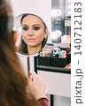 Beauty reflection. Makeup routine. Female checking facial cosmetic treatment using mirror in professional salon indoor. 140712183
