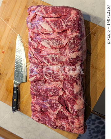 Raw Prime Ribeye Roast on Wooden Cutting Board with Chef Knife Showing Rich Marbling in Kitchen Raw Prime Ribeye Roast on Wooden Cutting Board with Chef Knife Showing Rich Marbling in Kitchen 140712267