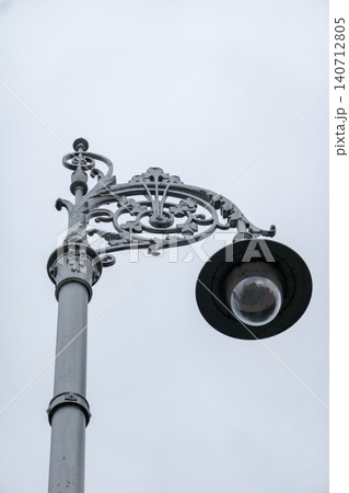 Ornate Vintage Street Lamp with Decorative Ironwork Against Gray Overcast Sky Minimal Urban  140712805