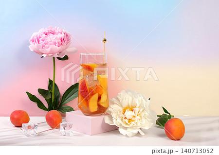 Modern still life with peonies and cocktail or tea with apricot, peach and ice cubes on sunny elegant background, summer party concept, minimalist abstract background for alcoholic drinks presentation 140713052
