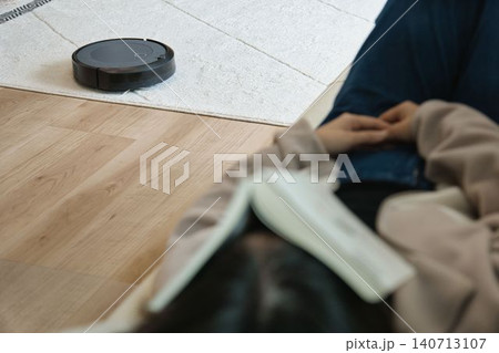 ロボット掃除機とソファで昼寝する人 140713107