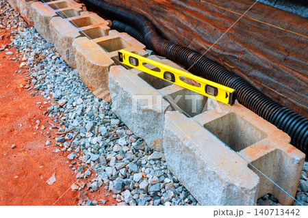 Cinder blocks are arranged on gravel with level tool placed on them at construction site 140713442