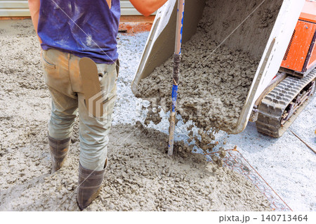 Worker uses mixer to pour wet concrete onto gravel while preparing construction project Worker uses mixer to pour wet concrete onto gravel while preparing construction project 140713464