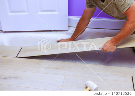 Carpenter works on laying new flooring in room with tools project takes place indoors. 140713526