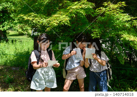 新緑の自然の中で地図を見てルートを発見し指差す女子小学生たち 新緑の自然の中で地図を見てルートを発見し指差す女子小学生たち 140714018