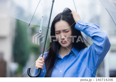 雨の中、傘をさす若い女性 雨の中、傘をさす若い女性 140714206