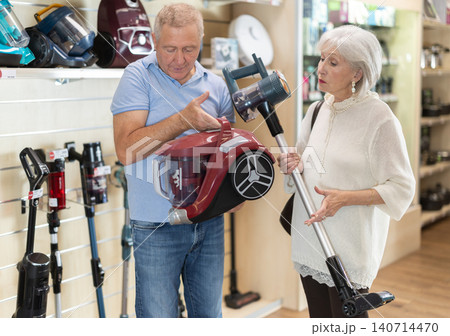 Elderly couple choosing a powerful vacuum cleaner together Elderly couple choosing a powerful vacuum cleaner together 140714470
