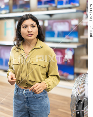 Visiting store young woman is looking at something on shelf of showcase 140714479