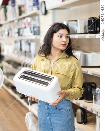 Latina woman looking at the assortment of toasters in the store Latina woman looking at the assortment of toasters in the store 140714486