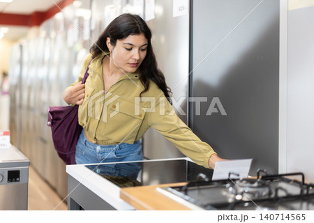 Mexican woman standing in store and choose induction cooker Mexican woman standing in store and choose induction cooker 140714565