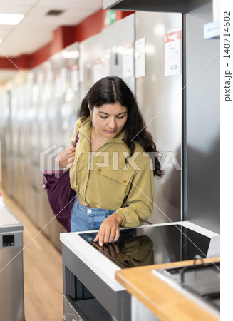 Beautiful young woman chooses and buys ceramic hob in hardware store Beautiful young woman chooses and buys ceramic hob in hardware store 140714602
