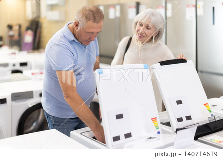 Elderly couple choosing a washing machine in a store Elderly couple choosing a washing machine in a store 140714619