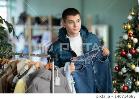 Guy client pre-examine fabric and style of product, is busy choosing jeans, X mas discount. 140714665