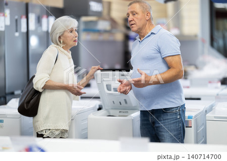 Elderly couple choosing a washing machine in a store Elderly couple choosing a washing machine in a store 140714700