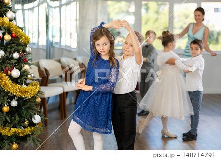 Little children practicing waltz dance in school-hall decorated with Christmas-tree Little children practicing waltz dance in school-hall decorated with Christmas-tree 140714791