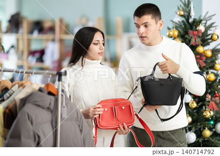Couple in love choosing a handbag in a Christmas shop Couple in love choosing a handbag in a Christmas shop 140714792
