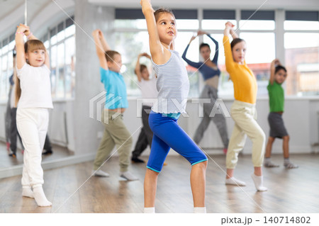 Children studying modern style dances with female teacher in dance class 140714802