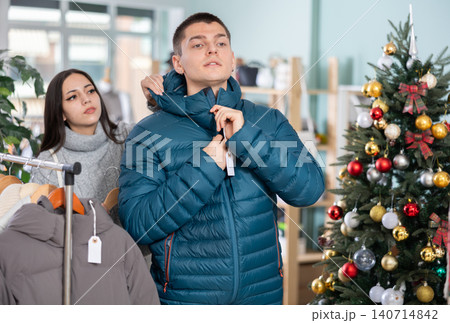 Young guy and his girlfriend try on down jacket Young guy and his girlfriend try on down jacket 140714842