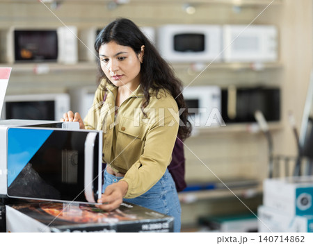 Young woman choosing microwave oven at household appliances store Young woman choosing microwave oven at household appliances store 140714862