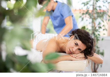 Masseur doing thigh massage to adult woman 140714864