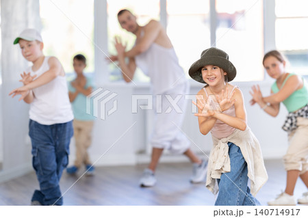 In sports studio, childrens team learns hip-hop dance accompanied by experienced man teacher In sports studio, childrens team learns hip-hop dance accompanied by experienced man teacher 140714917