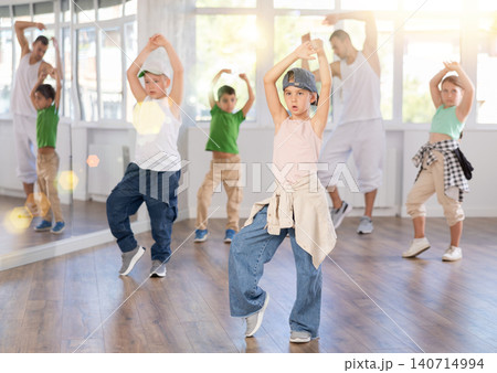 Expressive young girl learning modern street dancing during group class in choreographic studio 140714994